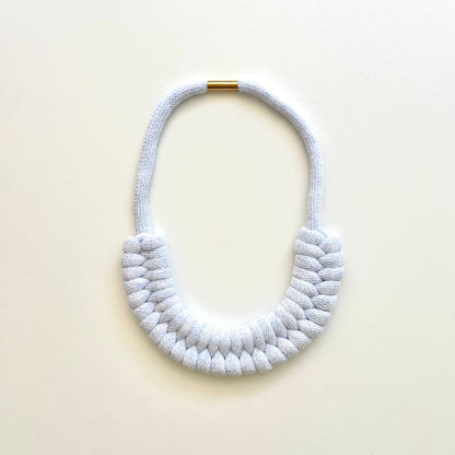 An ice blue, knotted necklace using the figure 8. The golden-look clasp is a sleek, minimal design. Made from 100% recycled cotton that is manufactured in the UK.