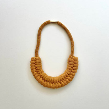 A mustard yellow, knotted necklace using the figure 8. The golden-look clasp is a sleek, minimal design. Made from 100% recycled cotton that is manufactured in the UK.