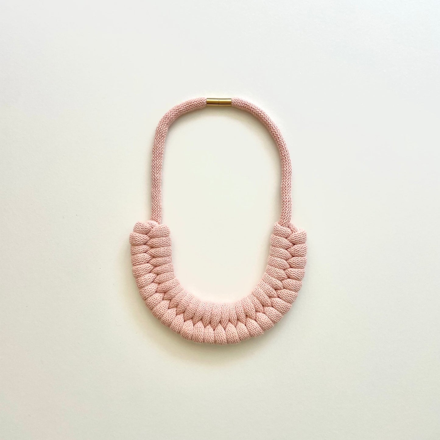 A baby pink, knotted necklace using the figure 8. The golden-look clasp is a sleek, minimal design. Made from 100% recycled cotton that is manufactured in the UK.