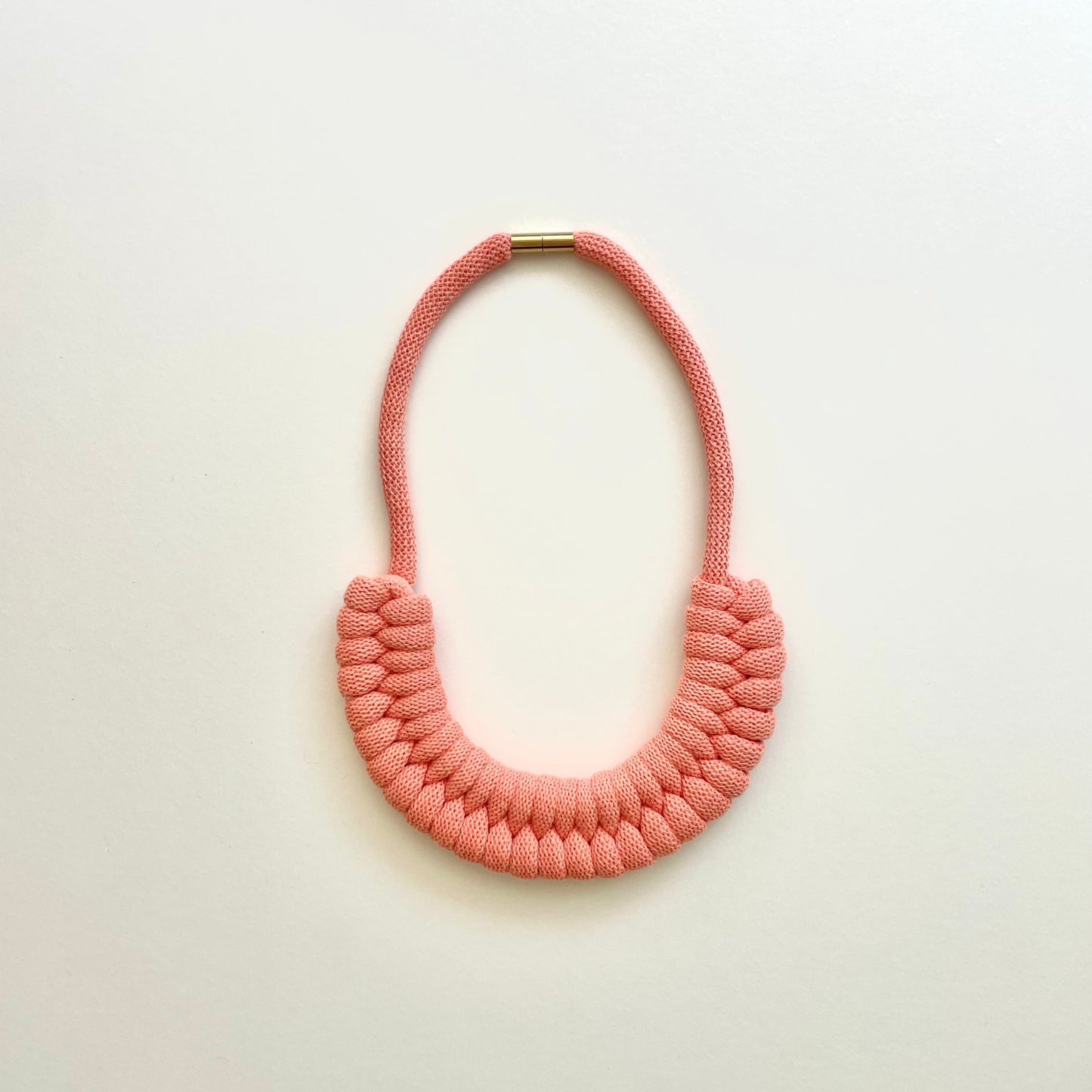 A peach coloured, knotted necklace using the figure 8. The golden-look clasp is a sleek, minimal design. Made from 100% recycled cotton that is manufactured in the UK.