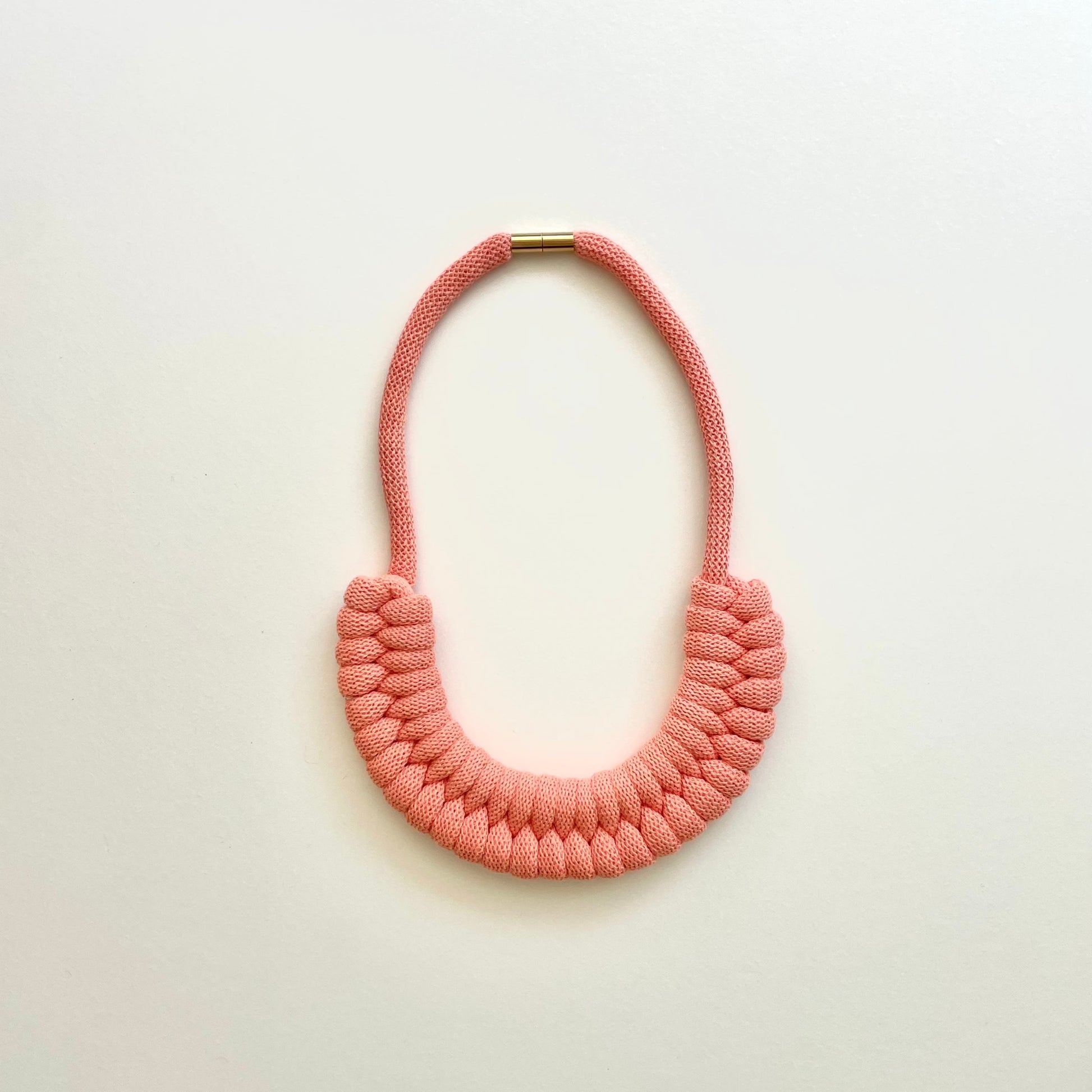 A peach coloured, knotted necklace using the figure 8. The golden-look clasp is a sleek, minimal design. Made from 100% recycled cotton that is manufactured in the UK.