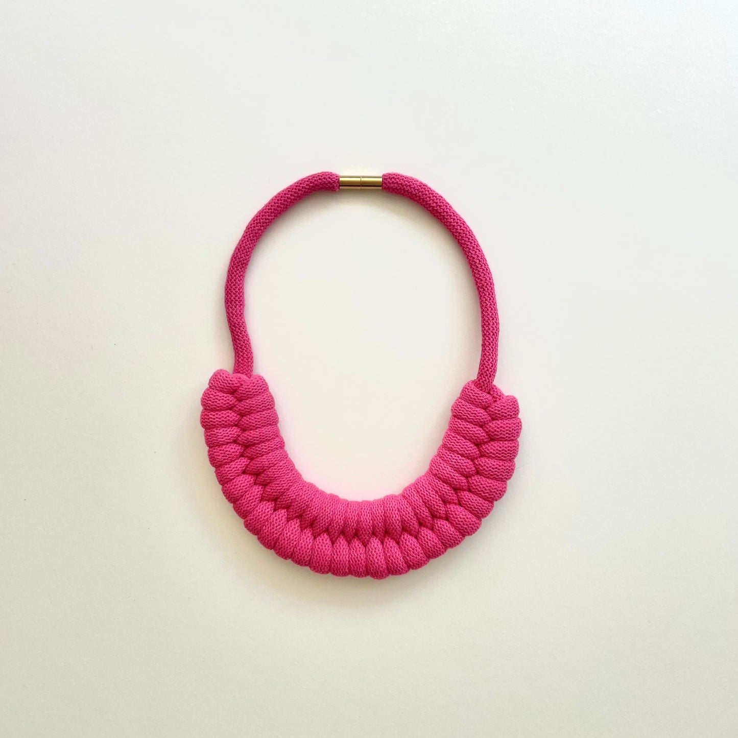 A fuchsia pink, knotted necklace using the figure 8. The golden-look clasp is a sleek, minimal design. Made from 100% recycled cotton that is manufactured in the UK.