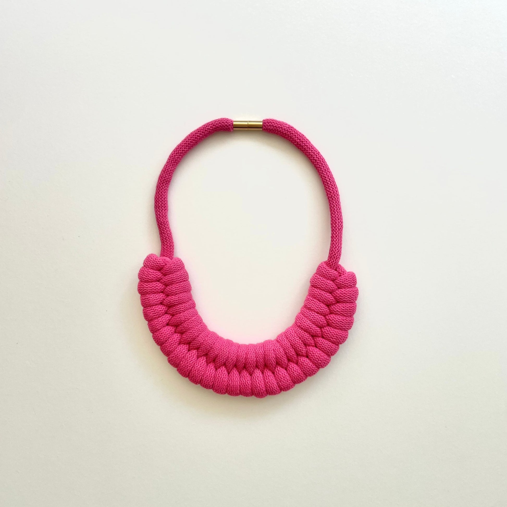 A fuchsia pink, knotted necklace using the figure 8. The golden-look clasp is a sleek, minimal design. Made from 100% recycled cotton that is manufactured in the UK.